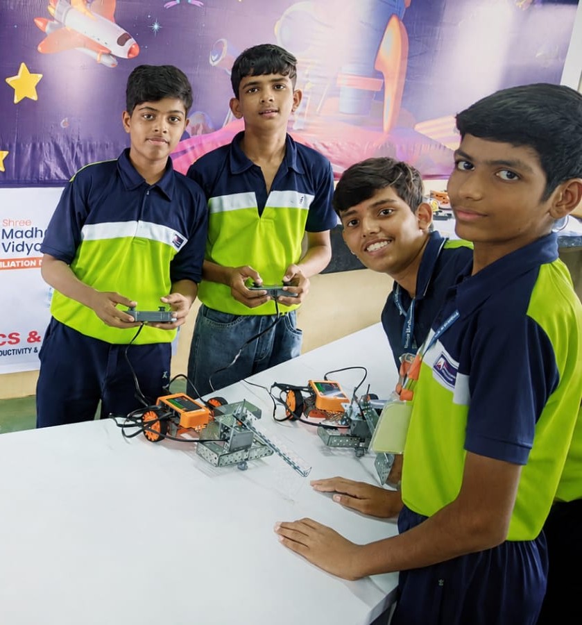 Edusmart students in green uniforms with wireless remote-controlled robotics cars
