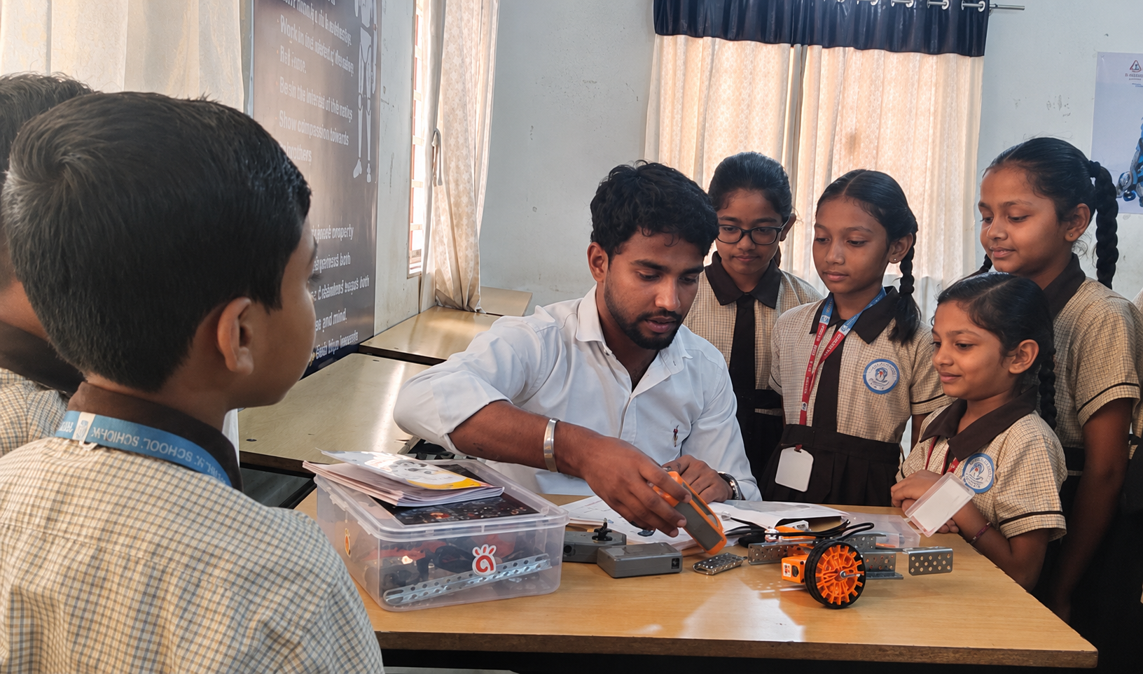Edusmart trainer demonstrating a robot kit to engaged school students in uniform, classroom setting