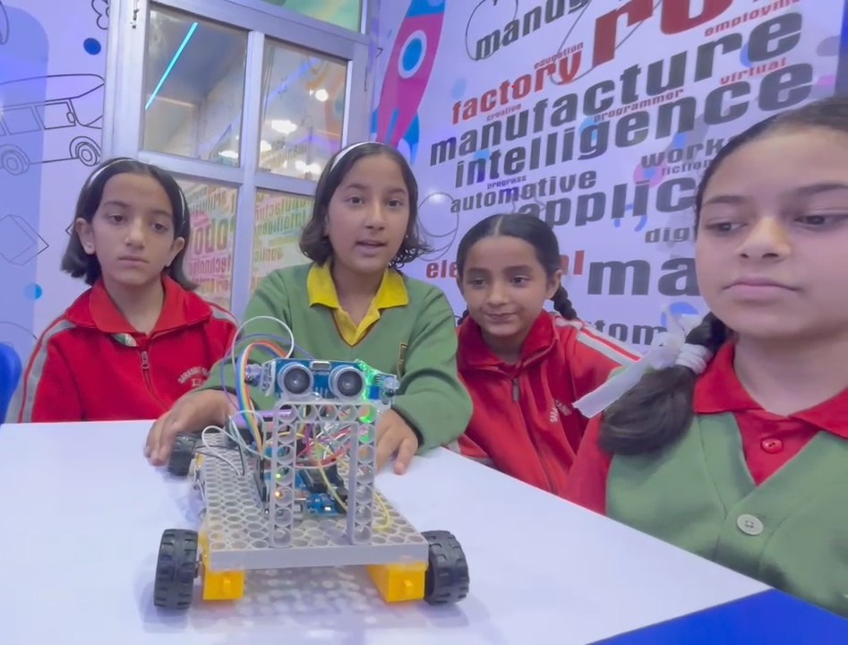 Four Edusmart students presenting their self-built obstacle-avoiding robot car at a STEM showcase